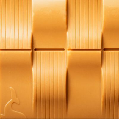 tablette de chocolat blond de La Baleine à Cabosse dans son emballage, posée à côté de la tablette de chocolat blond sans emballage