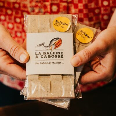 la tablette de chocolat blanc au riz au lait de La Baleine à Cabosse dans son emballage, avec un petit autocollant Refugee Food Festival