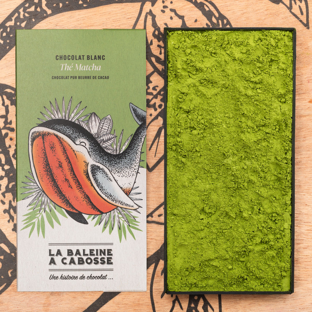 Tablette Chocolat blanc au thé matcha 1 Tablette Chocolat blanc au thé matcha de La Baleine à Cabosse dans son emballage, posée à côté d'un moule en forme de tablette rempli de poudre de matcha