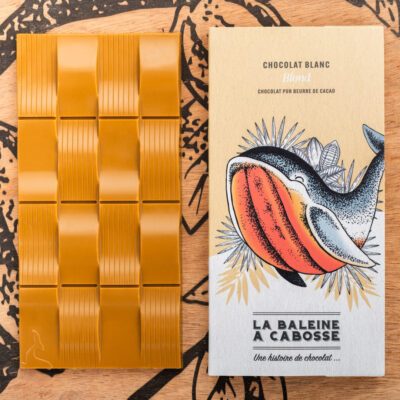 tablette de chocolat blond de La Baleine à Cabosse dans son emballage, posée à côté de la tablette de chocolat blond sans emballage