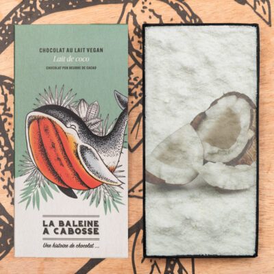 Tablette de chocolat au lait de coco 45% de cacao de La Baleine à Cabosse dans son emballage, posée à côté d'un moule en forme de tablette avec un visuel de la noix de coco