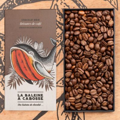 Tablette Chocolat noir 76% & brisures de café de La Baleine à Cabosse dans son emballage, posée à côté d'un moule en forme de tablette rempli de grains de café