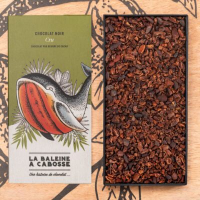 Tablette Chocolat Cru 76% de la Baleine à Cabosse dans son emballage, posée à côté d'un moule en forme de tablette rempli de grué de cacao