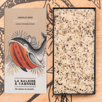 Tablette de chocolat noir 76% & sel vanillé de Mayotte de La Baleine à Cabosse dans son emballage, posée à côté d'un moule en forme de tablette rempli de sel vanillé