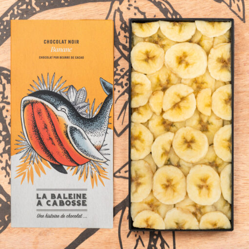 la tablette de chocolat noir 65% & banane de La Baleine à Cabosse dans son emballage, posée à côté d’un moule en forme de tablette rempli de rondelles de bananes
