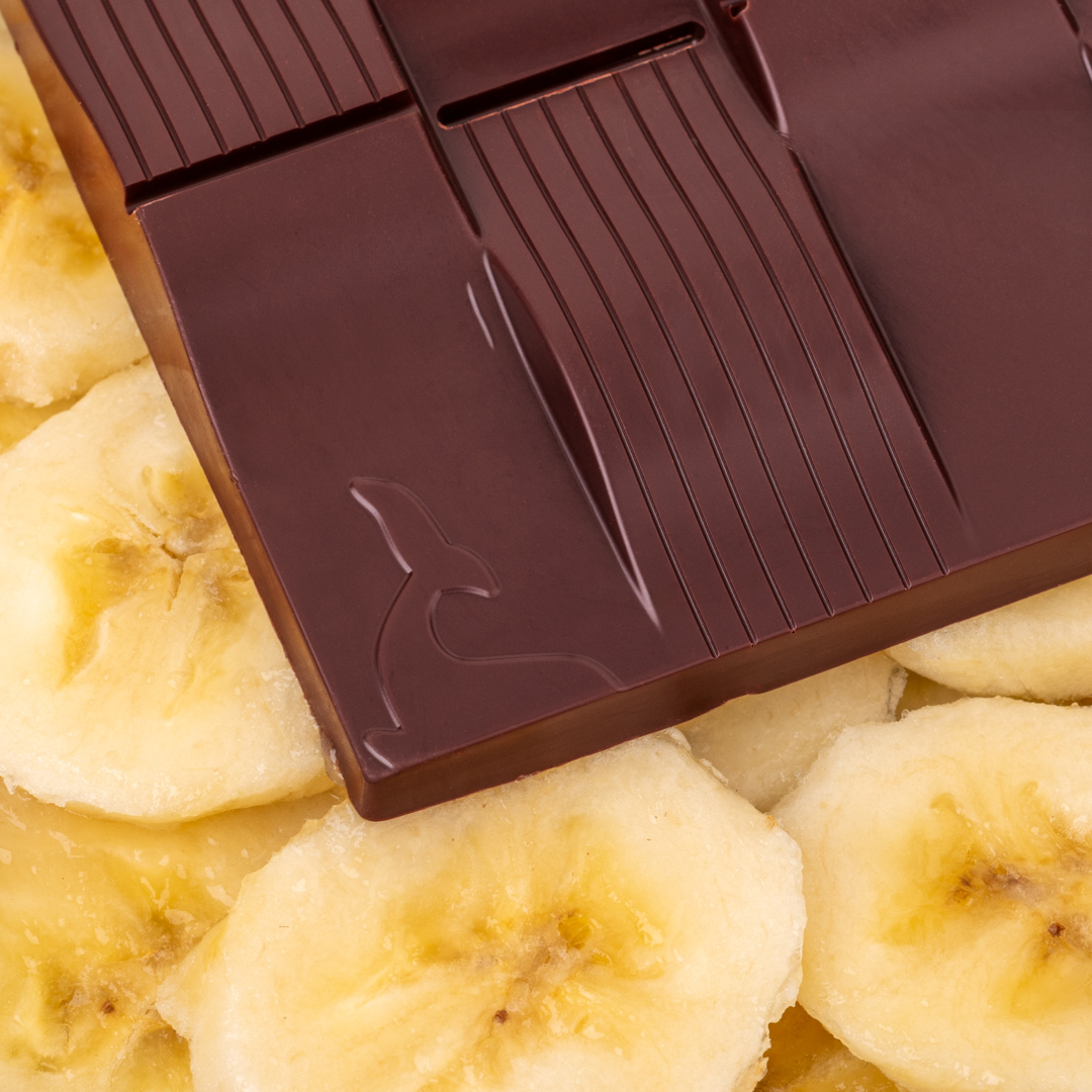 détail de la tablette de chocolat noir 65% & banane, sur fond de rondelles de bananes